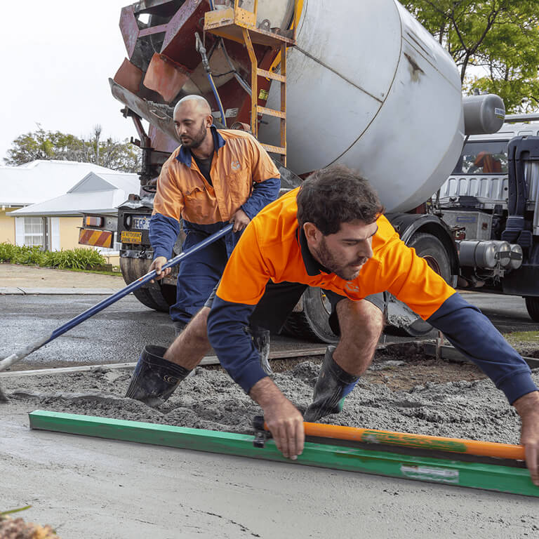 Council workers levelling wet concrete on a residential street.