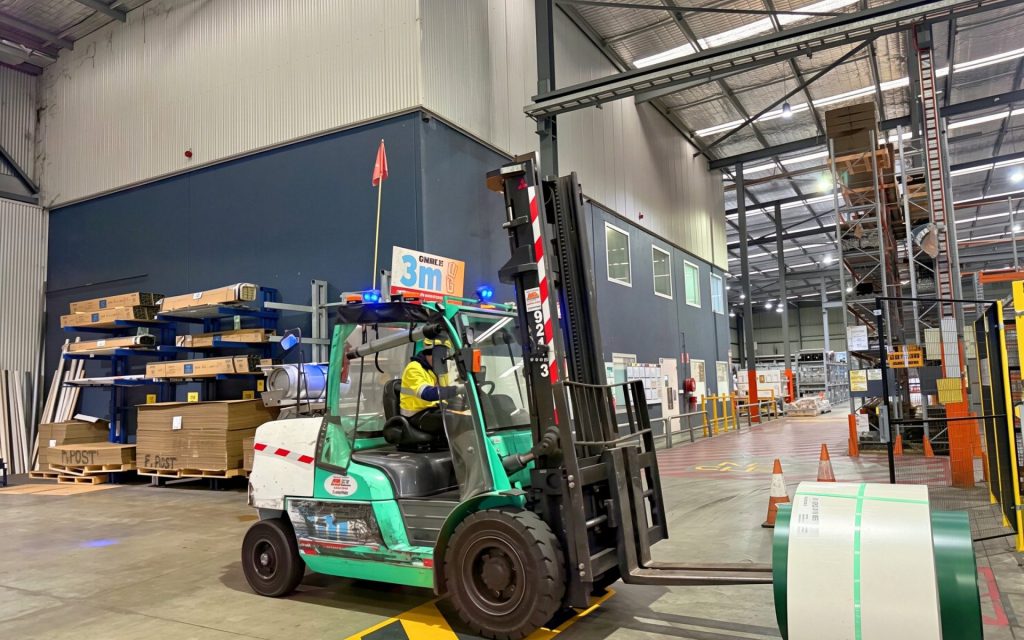 Forklift carrying a steel coil across the warehouse floor