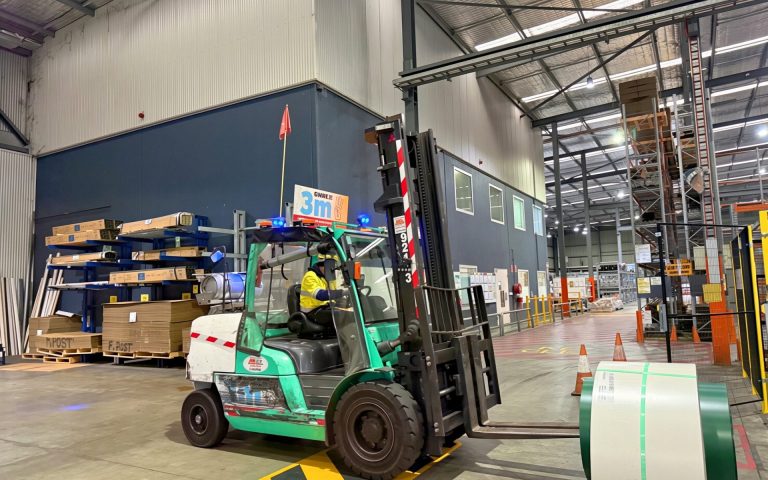 Forklift carrying a steel coil across the warehouse floor
