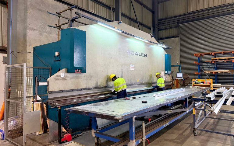 Two workers folding sheet metal on a wide press brake